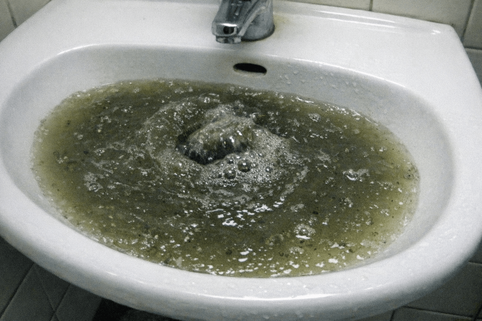 Gluckerndes Wasser staut sich in einem weißen Keramikbecken